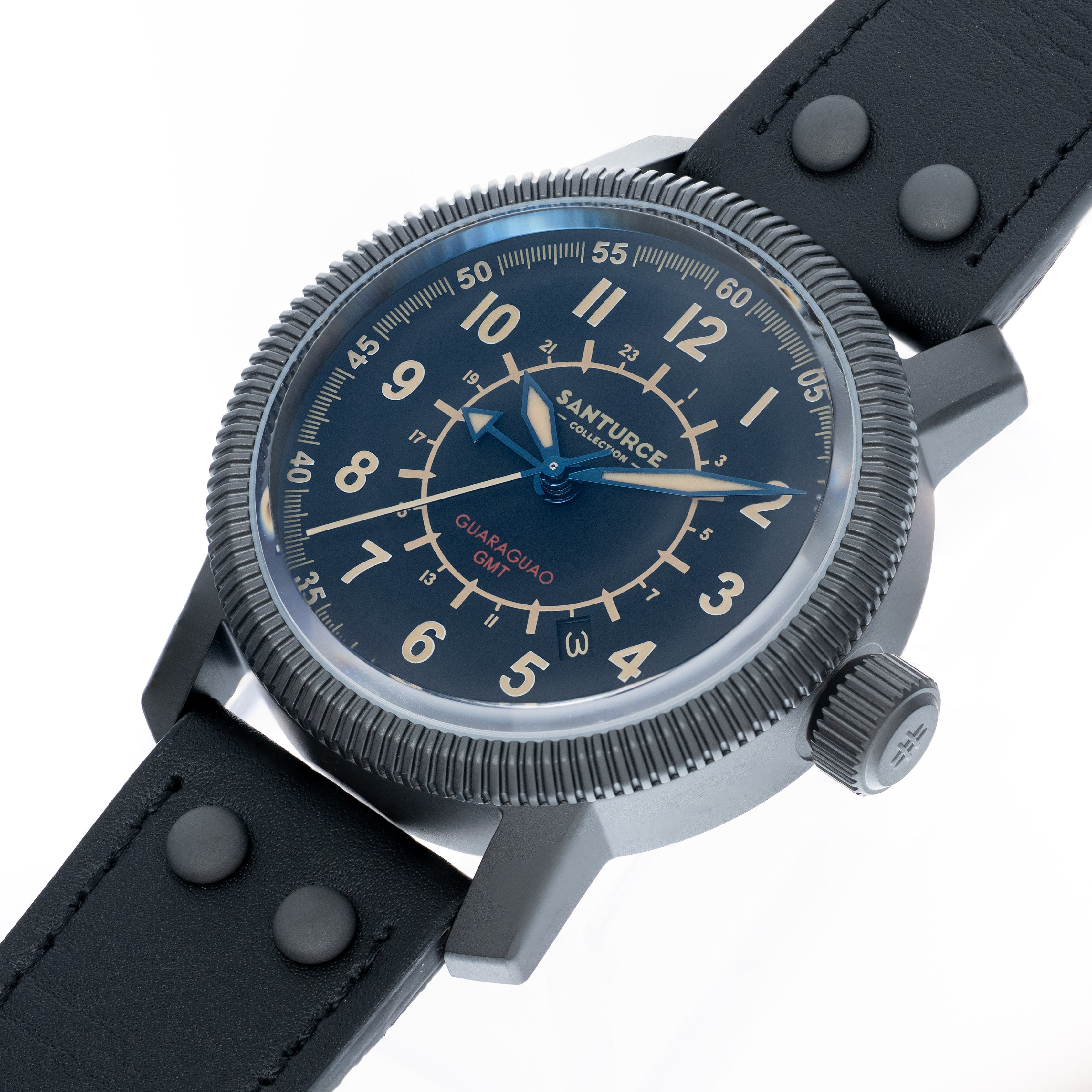 A close-up of a Santurce Guaraguao GMT watch with a dark dial, PVD case  and black strap on a white background.