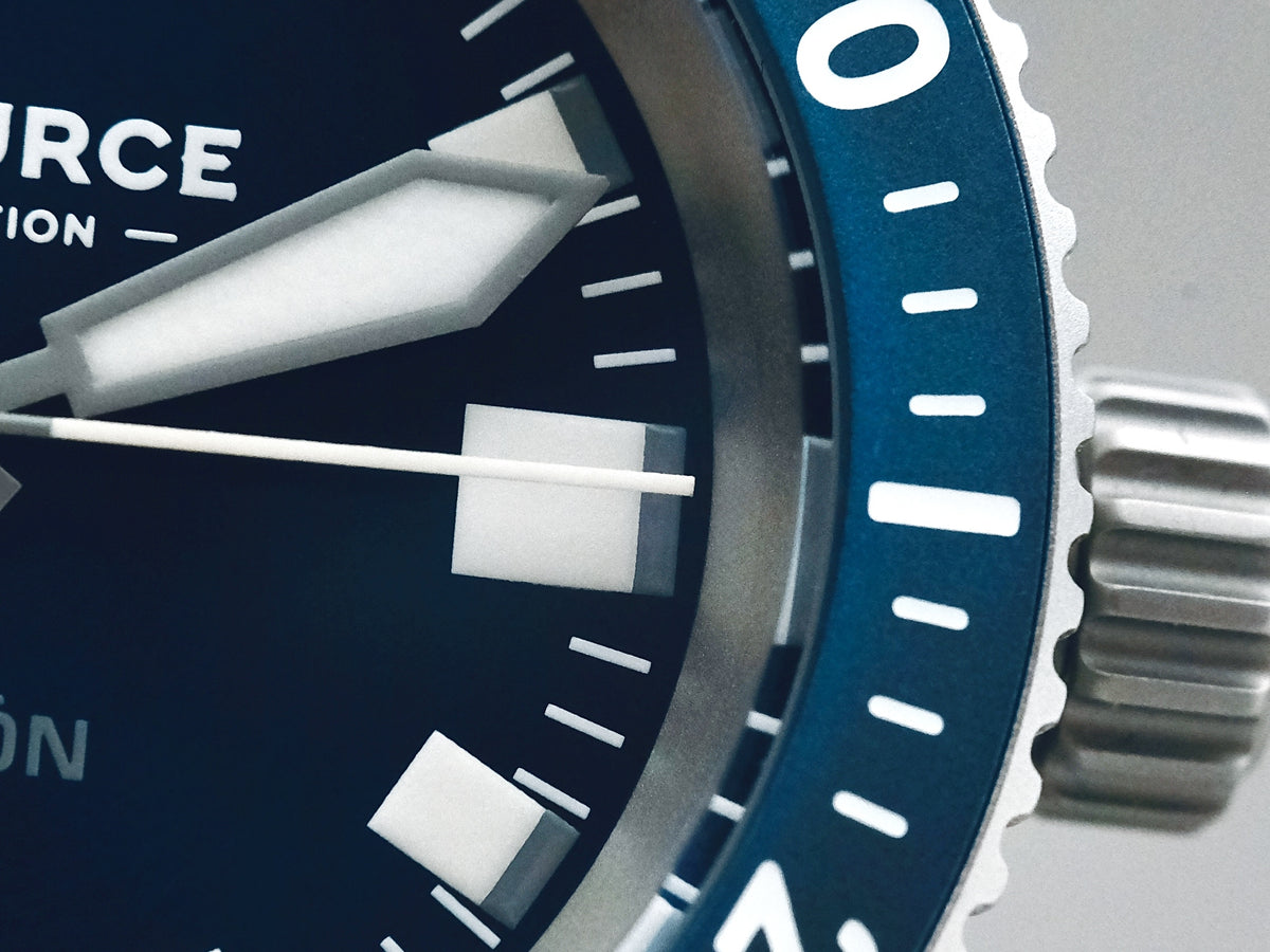 A close view of the dial, luminous markers and blue bezel.
